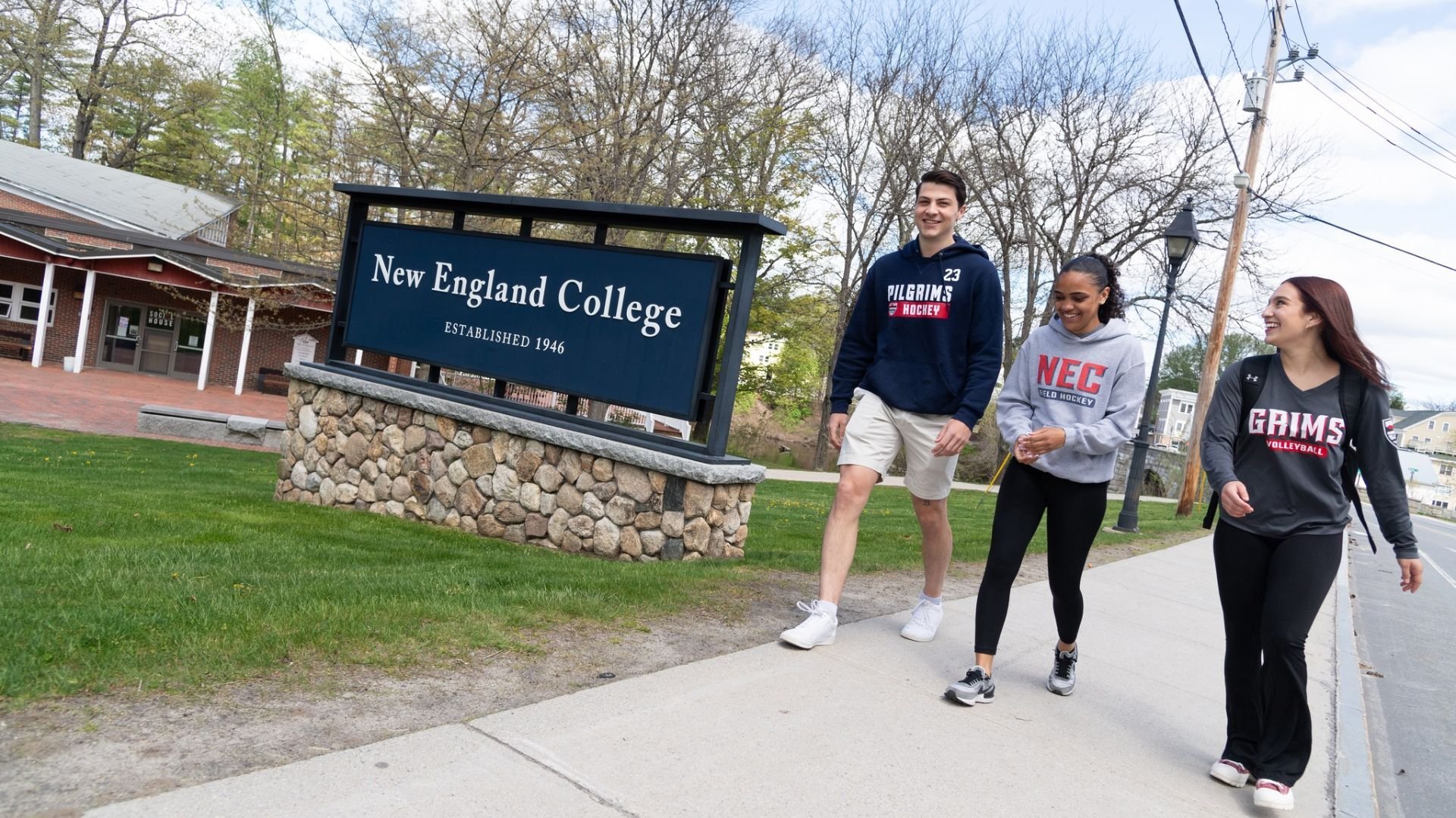 new england college students walking in front of signage